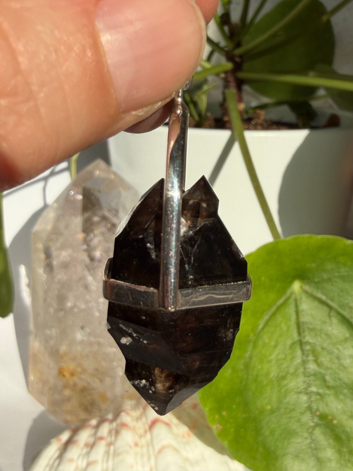 Mooralla Smokey Quartz crystal set into a silver pendant showing the side angle with a nature background