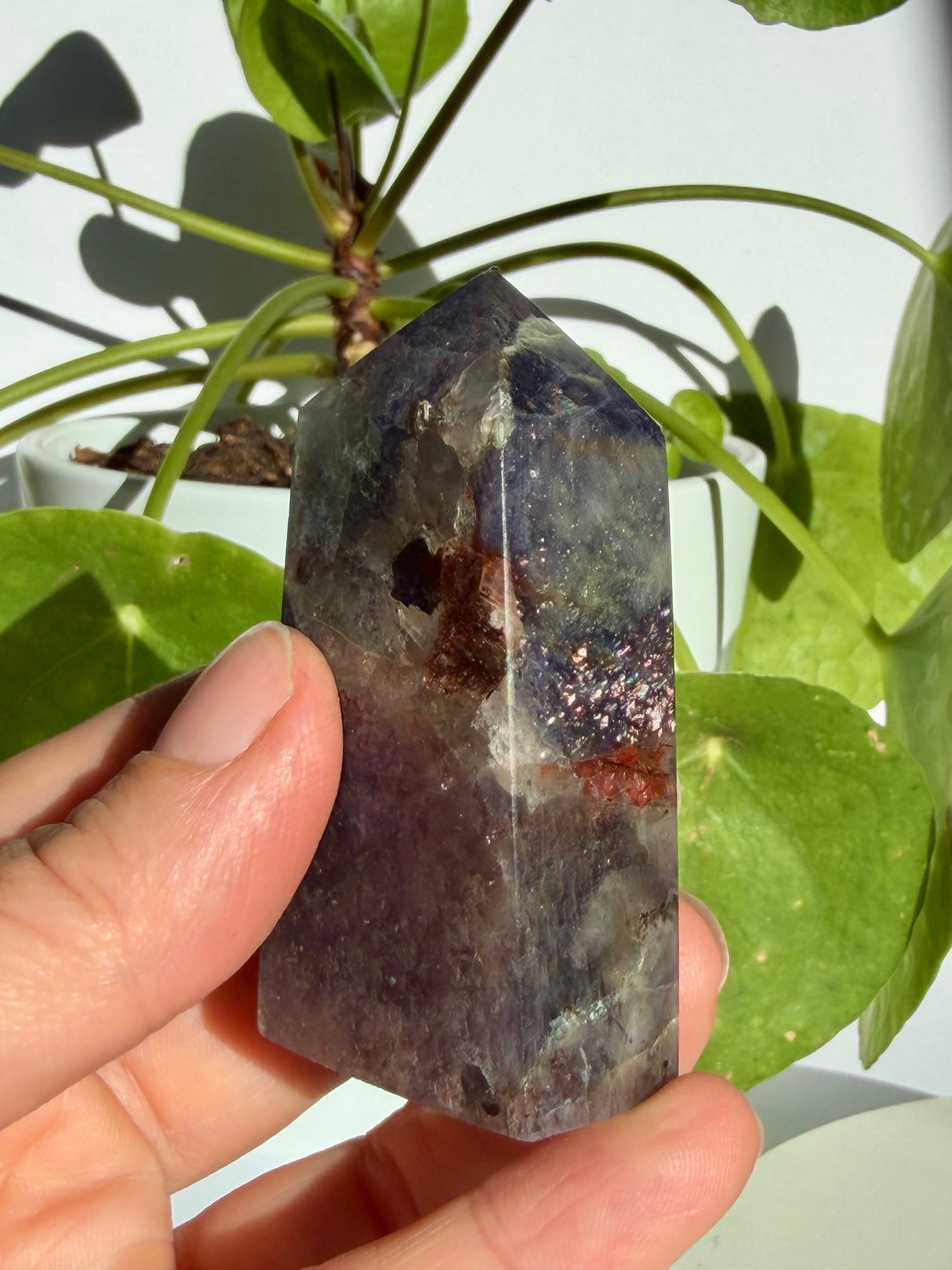 Sunstone in iolite point photographed near the tip, showing a small clear window above a rust-coloured inclusion patch
