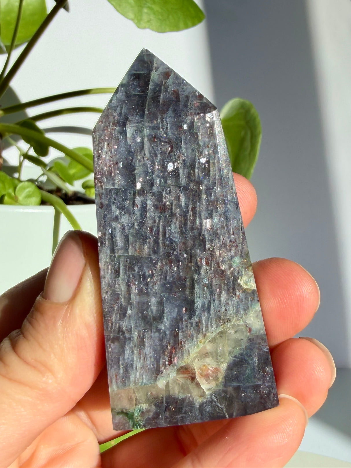 Sunstone in iolite point with fine vertical striations and scattered copper-red sparkle across a deep grey-violet body