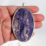 Purple Charoite large oval pendant in sterling silver sitting on a hand