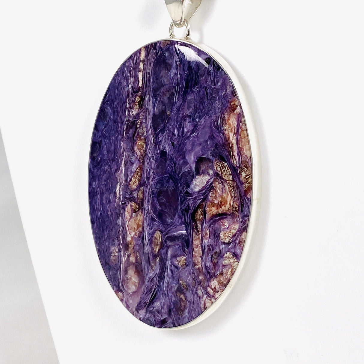 Purple Charoite large oval pendant in sterling silver sitting on a white background