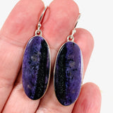Purple Charoite oval earrings in sterling silver sitting on a hand