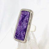 Purple Charoite rectangle ring in sterling silver sitting on a crystal cluster 