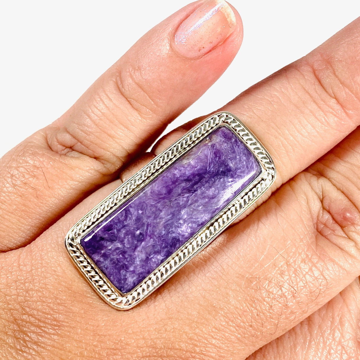 Purple Charoite rectangle ring in sterling silver shown on a hand