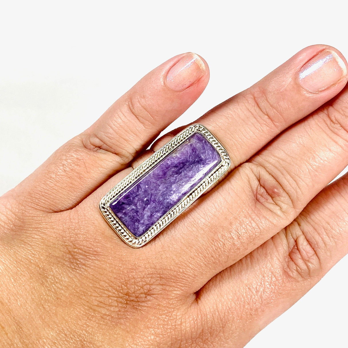 Purple Charoite rectangle ring in sterling silver shown on a hand