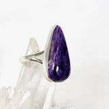 Purple Charoite tear drop ring in sterling silver sitting on a crystal cluster