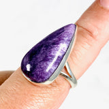 Purple Charoite tear drop ring in sterling silver sitting on a hand
