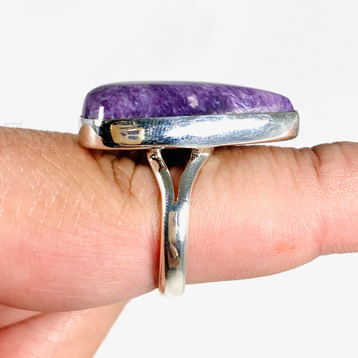 Purple Charoite tear drop ring in sterling silver sitting on a hand