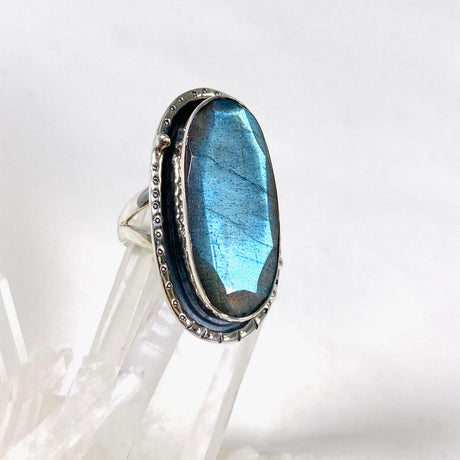 Blue iridescent Labradorite faceted gemstone ring set in silver on a clear quartz crystal