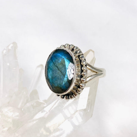 Blue iridescent Labradorite faceted gemstone and silver ring on a clear quartz crystal