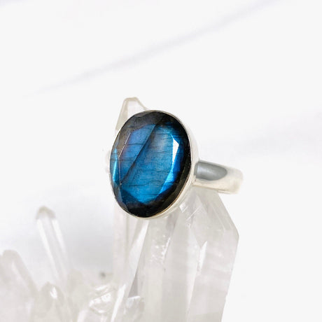 Blue iridescent Labradorite faceted gemstone and silver ring on a clear quartz crystal
