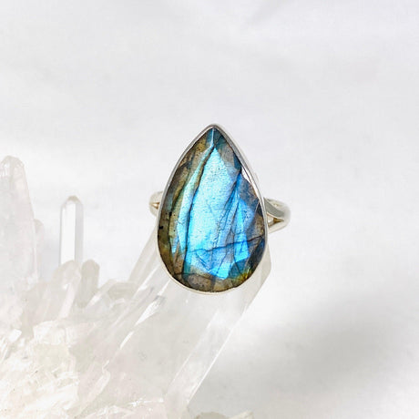 Blue iridescent Labradorite faceted gemstone and silver ring on a clear quartz crystal