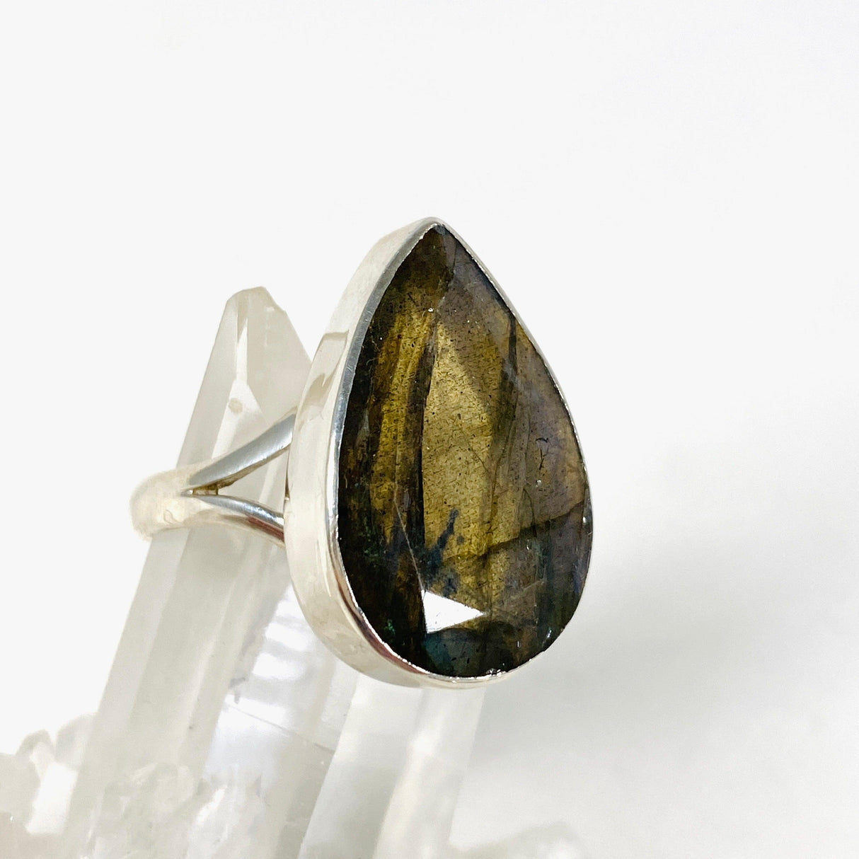 Blue iridescent Labradorite faceted gemstone and silver ring on a clear quartz crystal