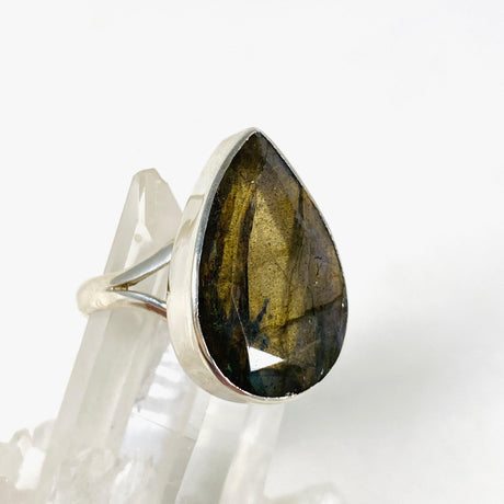 Blue iridescent Labradorite faceted gemstone and silver ring on a clear quartz crystal