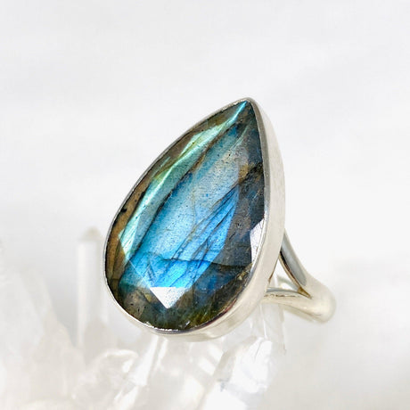 Blue iridescent Labradorite faceted gemstone and silver ring on a clear quartz crystal