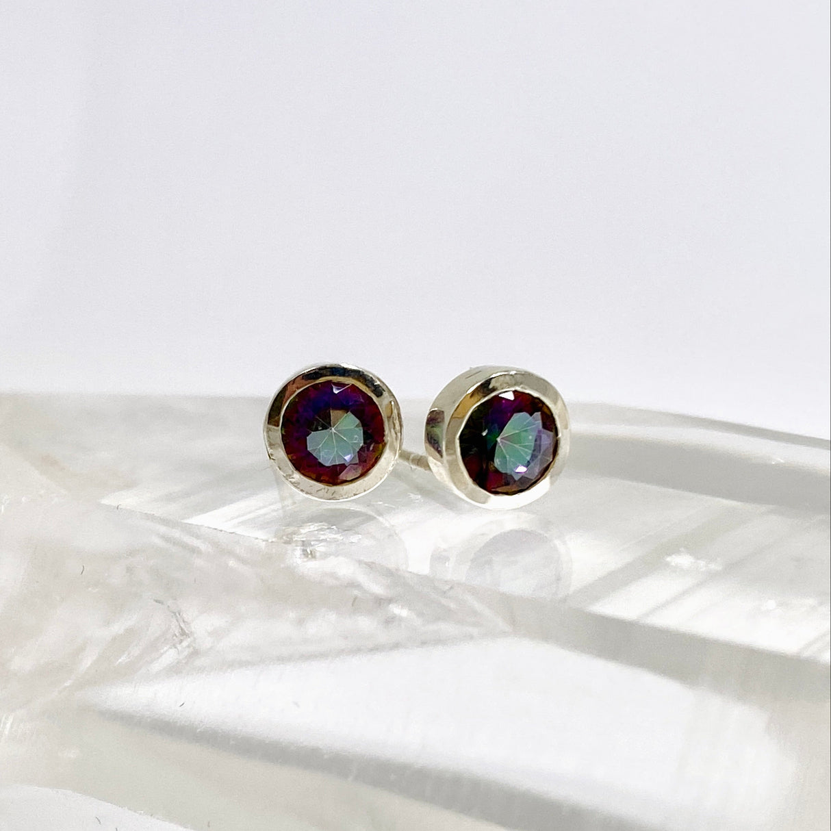 Multicolored gemstone stud earrings on a white surface