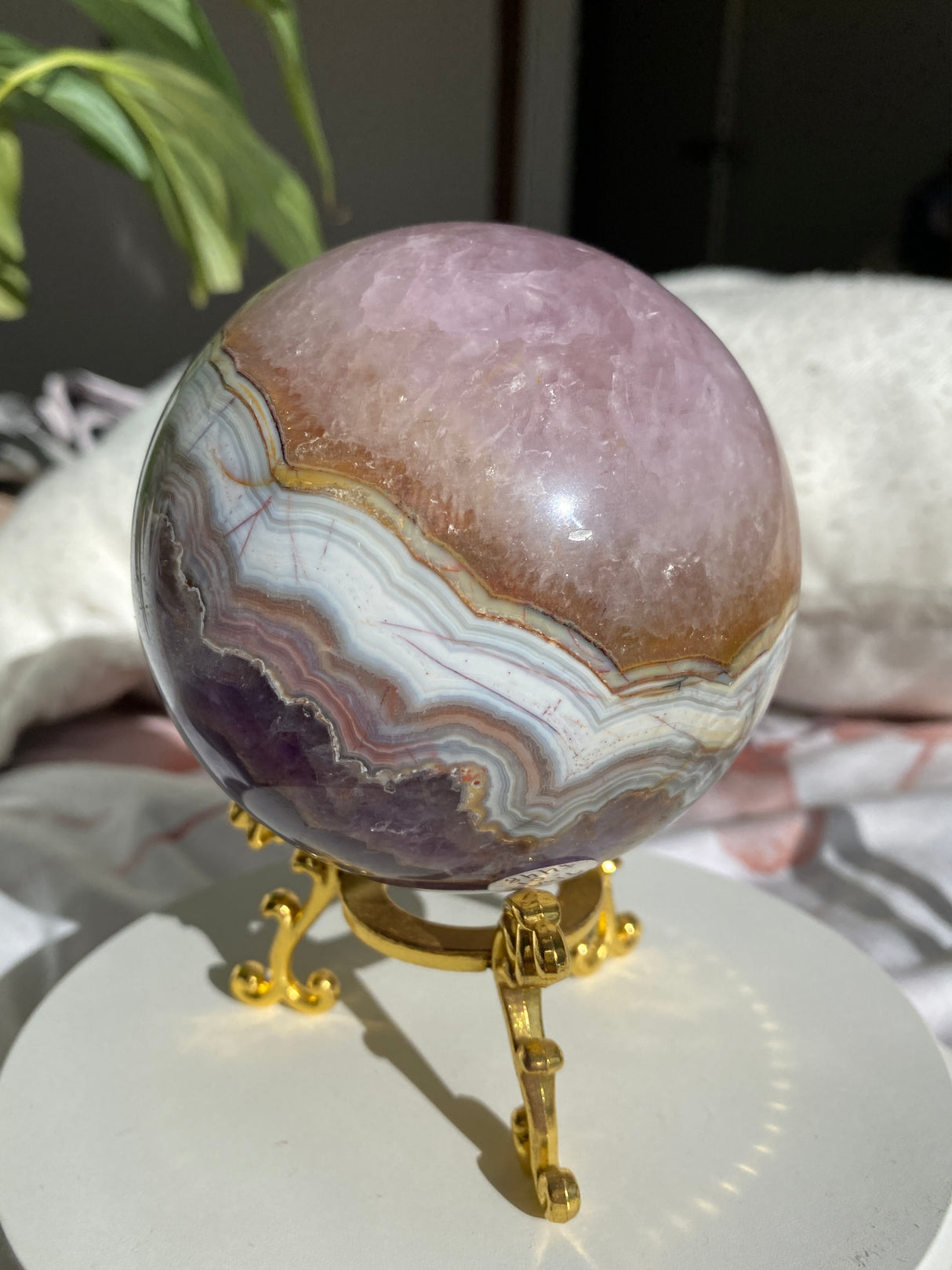 Decorative object with a purple and brown stone and gold accents on a white surface.