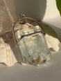 Aquamarine Crystal with muscovite pendant with silver setting on a seashell in the sunlight