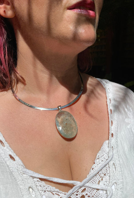 Close-up of a person wearing an aquamarine pendant.