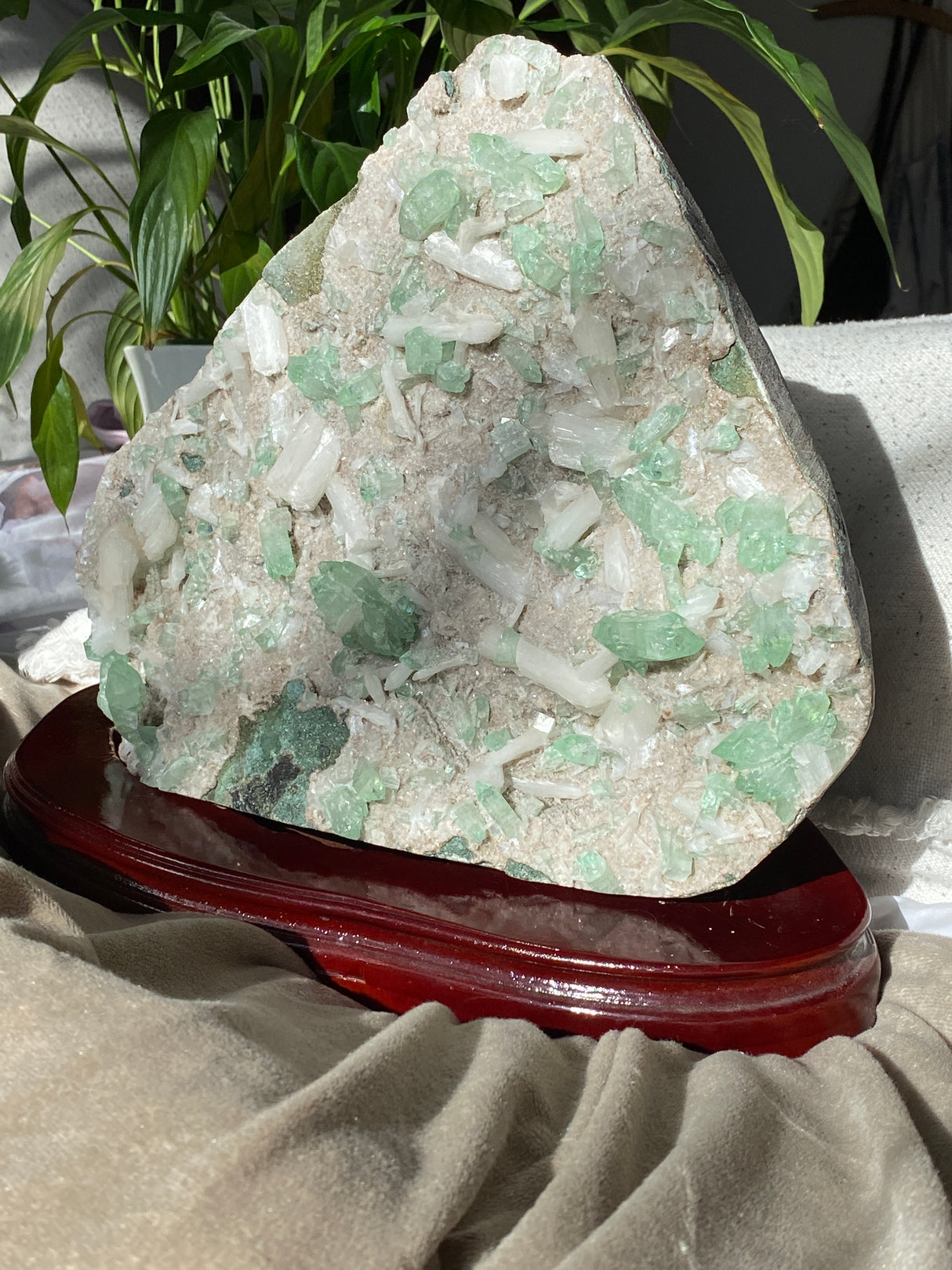 Mineral sample on a stand with green crystals and white matrix