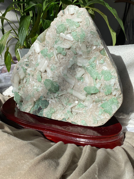 Mineral sample on a stand with green crystals and white matrix