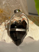 Crystal pendant with silver setting on a shell