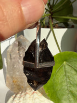 Mooralla Smokey Quartz crystal set into a silver pendant showing the side angle with a nature background 
