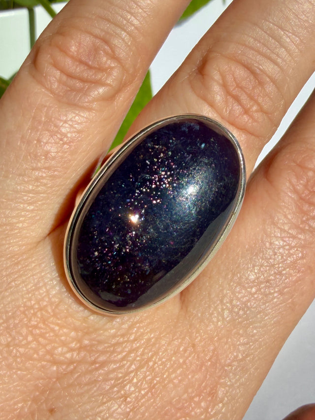 Sunstone in iolite oval cabochon in close view, with a dense vertical cluster of fine sparkle through the centre of the stone
