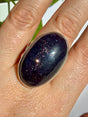 Sunstone in iolite oval cabochon in close view, with a dense vertical cluster of fine sparkle through the centre of the stone