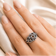 Silver ring with pentagram design on a wooden surface and being worn on a hand.