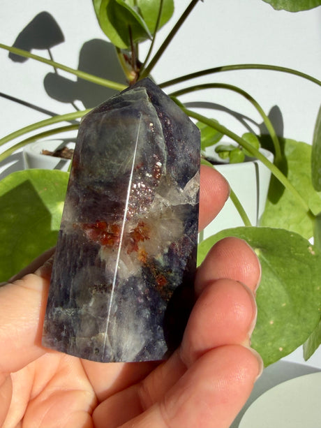 Sunstone in iolite crystal point in natural light, with sparkle concentrated near the top and a pale quartz pocket below