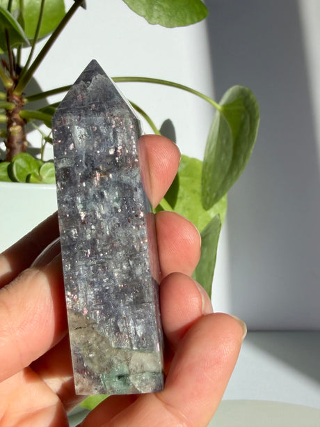 Sunstone in iolite point showing a pale smoky quartz zone at the base beneath a dense sparkling upper section, with a faint green trace visible