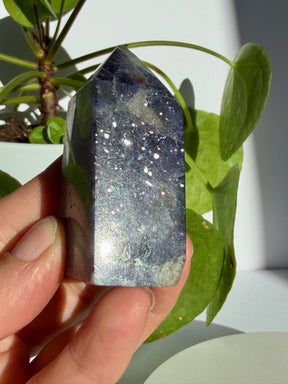 Sunstone in iolite crystal point covered in fine, star-like silver sparkle across a deep violet-grey body