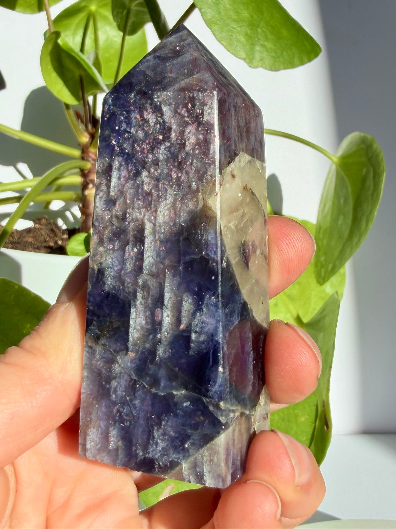 Sunstone in iolite point with a pale smoky-grey inclusion breaking through the sparkling violet upper body, deepening to indigo-blue near the base