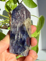 Sunstone in iolite point with a pale smoky-grey inclusion breaking through the sparkling violet upper body, deepening to indigo-blue near the base