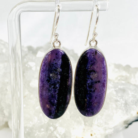 Purple Charoite oval earrings in sterling silver sitting on a crystal cluster
