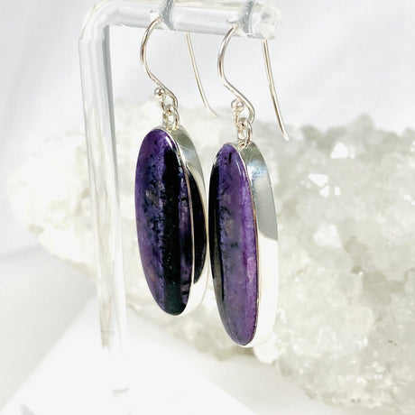 Purple Charoite oval earrings in sterling silver sitting on a crystal cluster