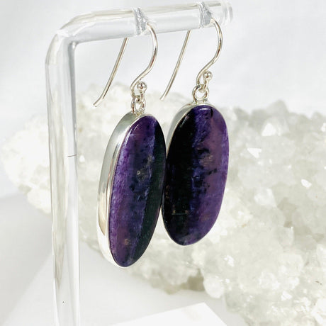 Purple Charoite oval earrings in sterling silver sitting on a crystal cluster