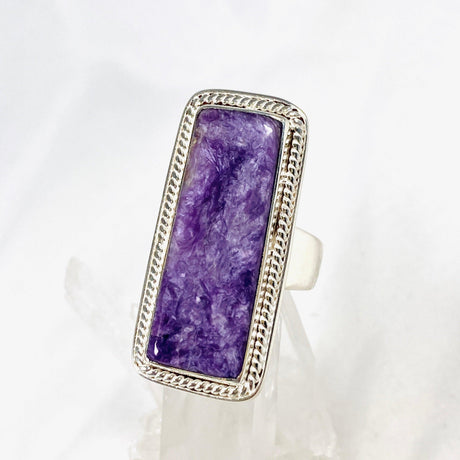 Purple Charoite rectangle ring in sterling silver sitting on a crystal cluster 