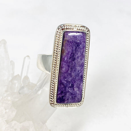 Purple Charoite rectangle ring in sterling silver sitting on a crystal cluster 