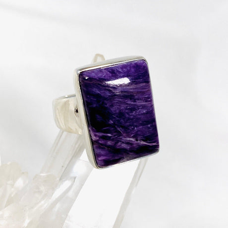 Purple Charoite rectangular ring in sterling silver sitting on a crystal cluster