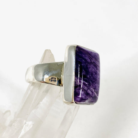 Purple Charoite rectangular ring in sterling silver sitting on a crystal cluster