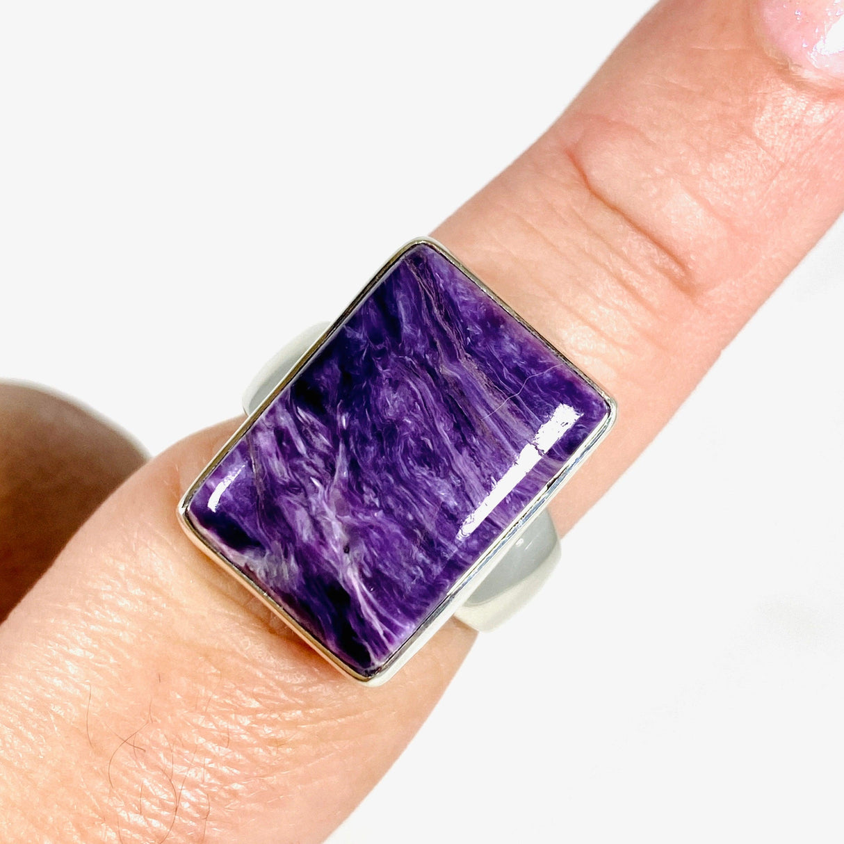 Purple Charoite rectangular ring in sterling silver sitting on a hand