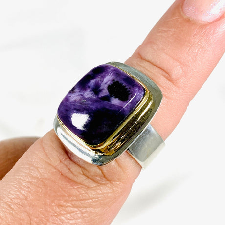 Purple Charoite rectangular ring with brass detailing in sterling silver sitting on a hand