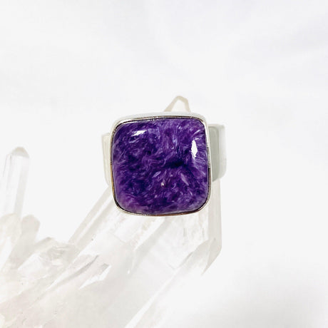 Purple Charoite square ring in sterling silver sitting on a crystal cluster