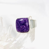 Purple Charoite square ring in sterling silver sitting on a crystal cluster