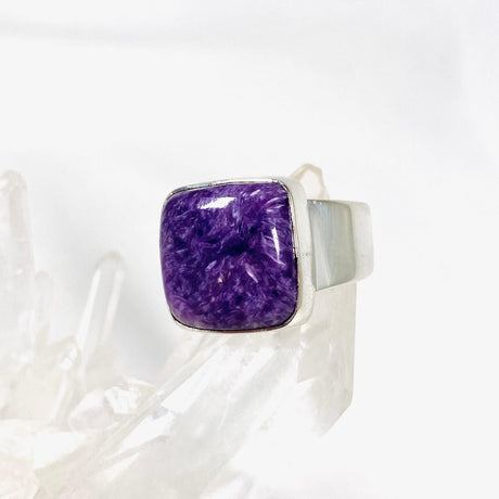 Purple Charoite square ring in sterling silver sitting on a crystal cluster