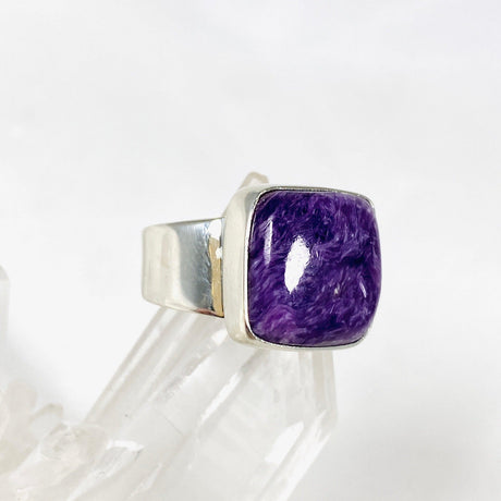 Purple Charoite square ring in sterling silver sitting on a crystal cluster