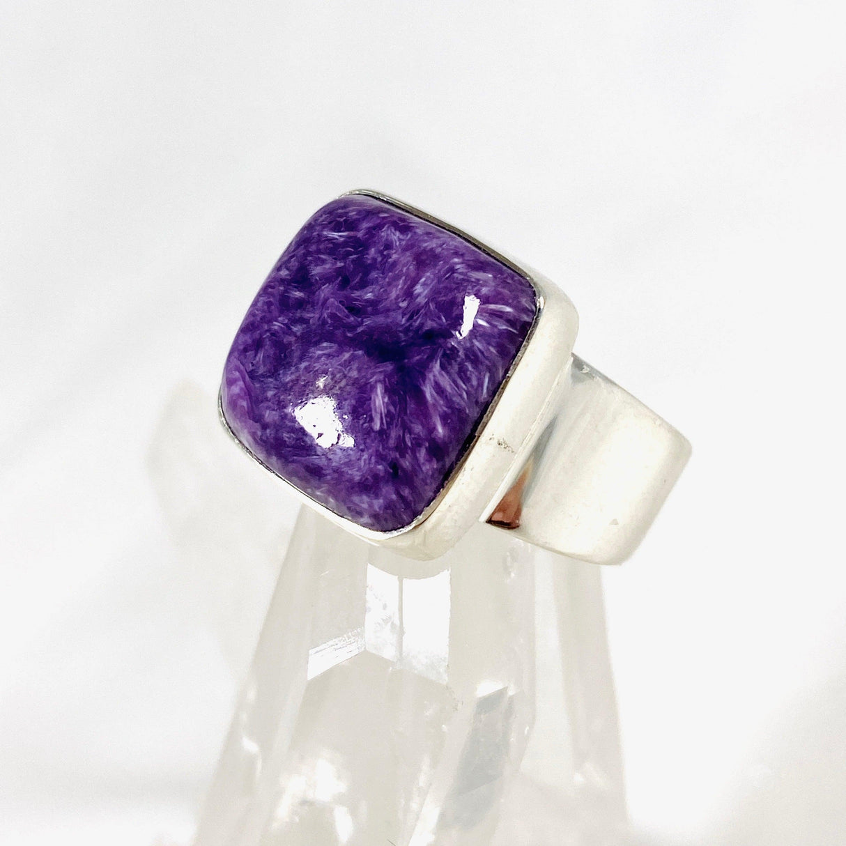 Purple Charoite square ring in sterling silver sitting on a crystal cluster
