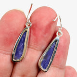 Purple Charoite tear drop earrings in sterling silver sitting in a hand